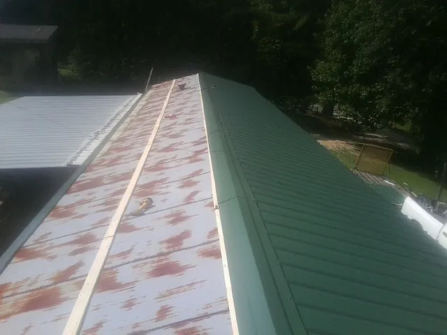 Old rusted panels beside newly installed green metal roofing — Wind Damage Roof Repair by Roofing Brothers in Stanfield