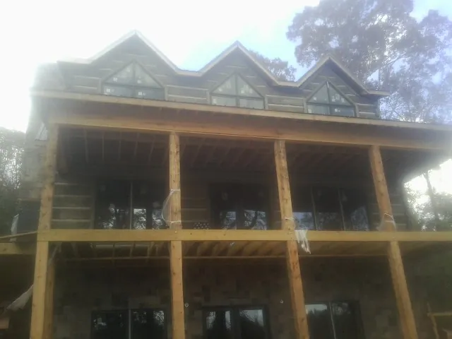 Dormers and porch framing on a large log home under construction — Roof Coating work by our crew in Stanfield